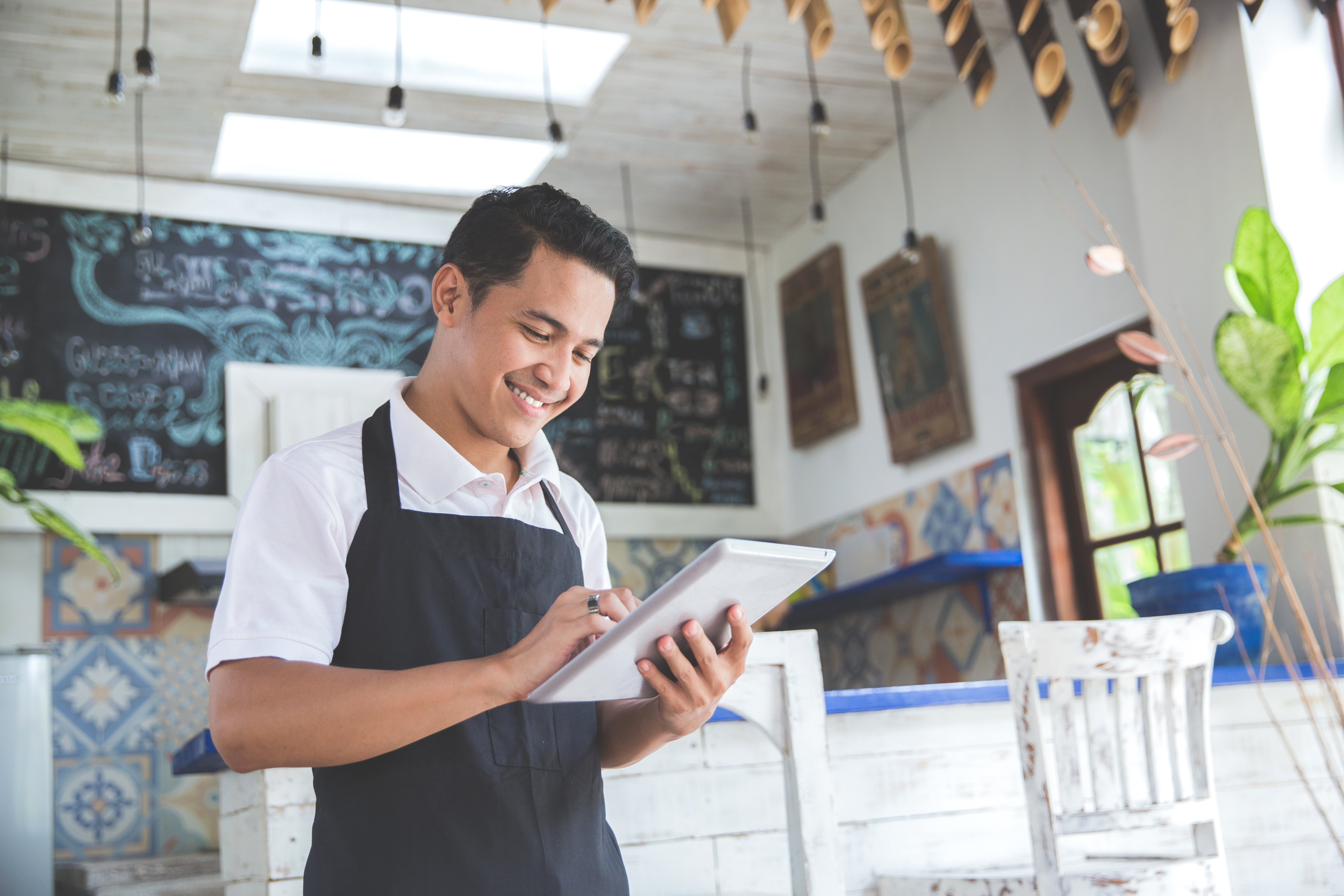 young male cafe employee working on tablet