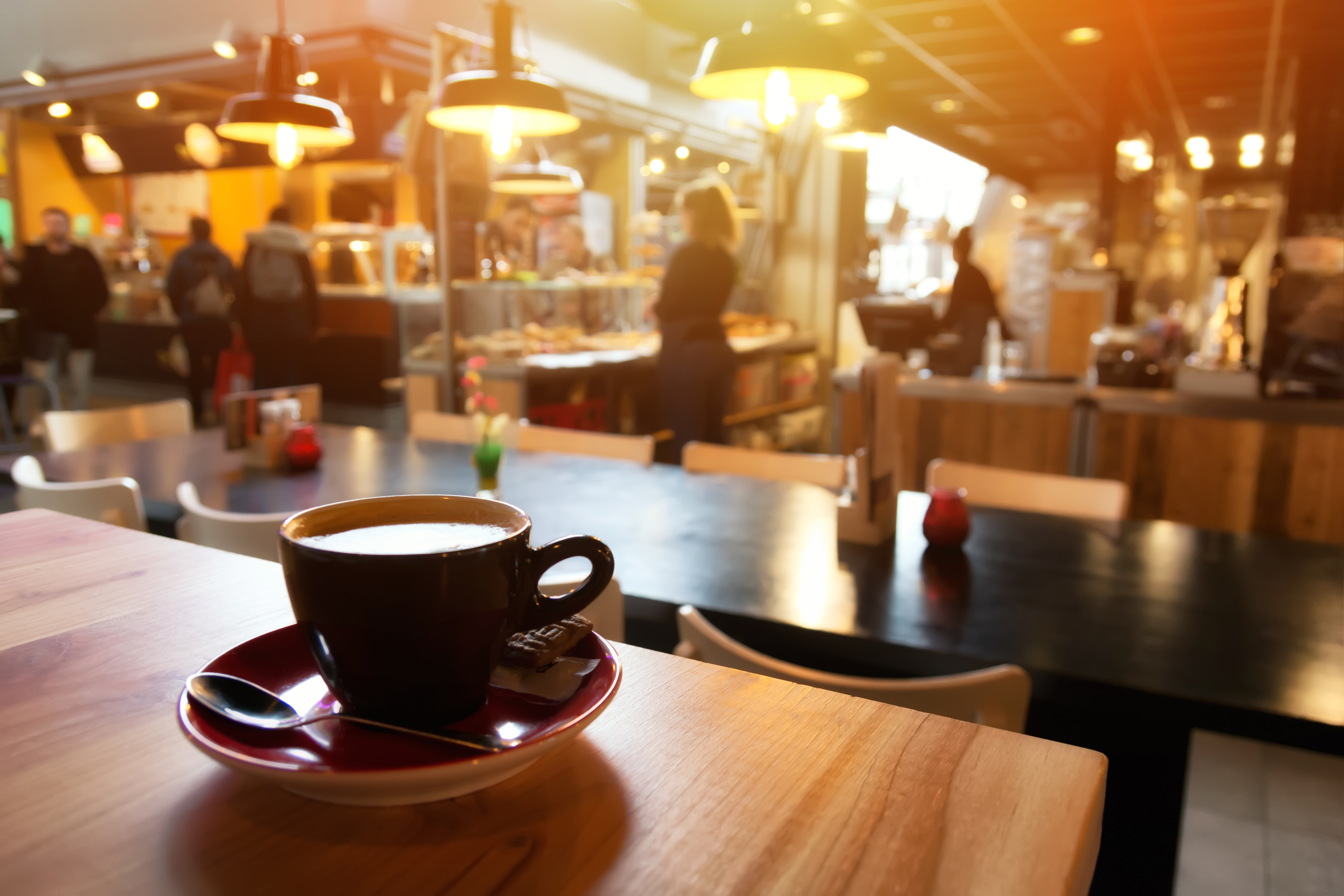 Coffee cup on wooden table with blur coffee shop background.